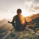 Man meditating yoga at sunset mountains