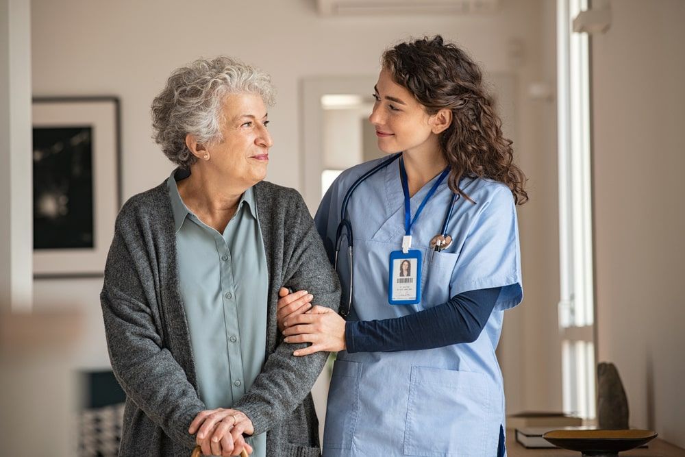 Nurse assisting her old woman patient at nursing home
