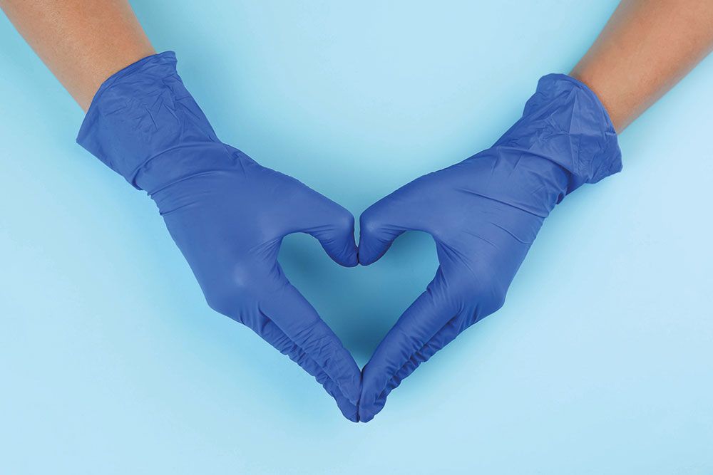 Hands with blue gloves creating heart