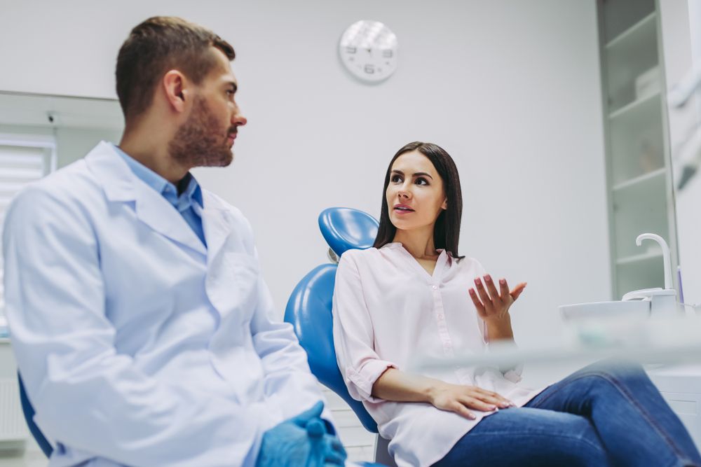 Female patient in dental chair and male dentist talking in dental clinic