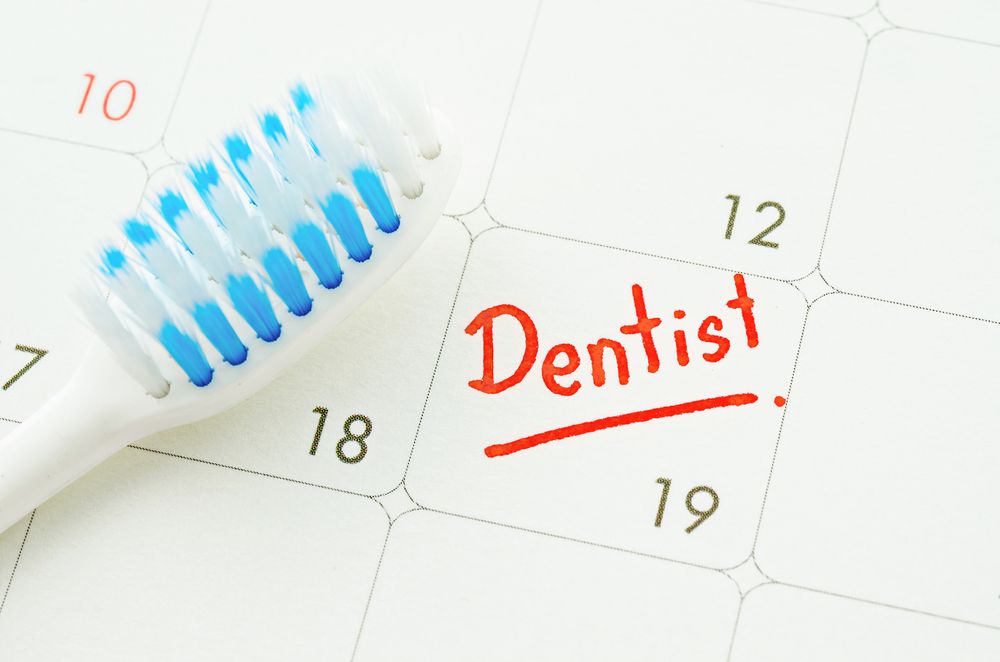 Blue toothbrush on dentist appointment reminder on a calendar page