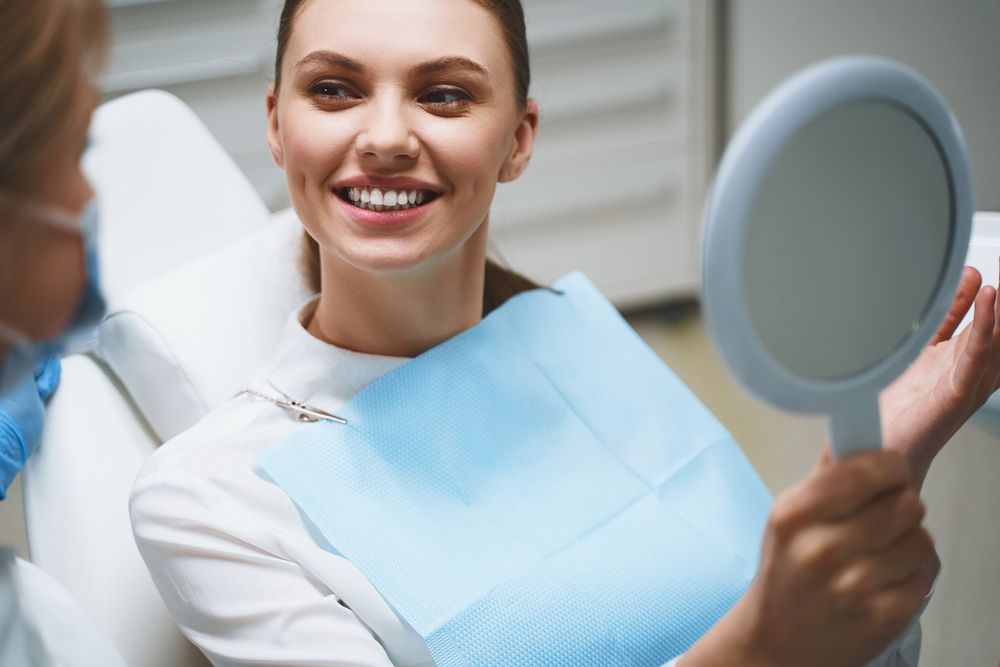 Delighted young girl in dental chair is talking with doctor