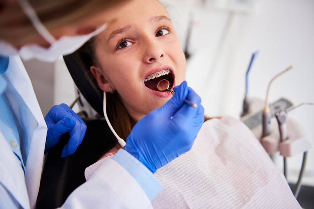 Orthodontist examining child's teeth in dentist's office