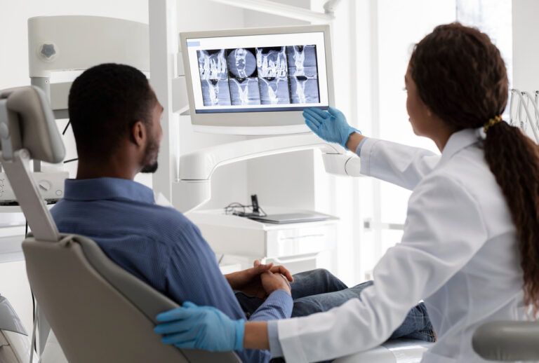 Female dentist pointing at screen with x-ray picture, showing patient his teeth