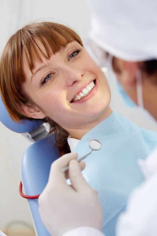 smiling patient looking at the dentist with mirror