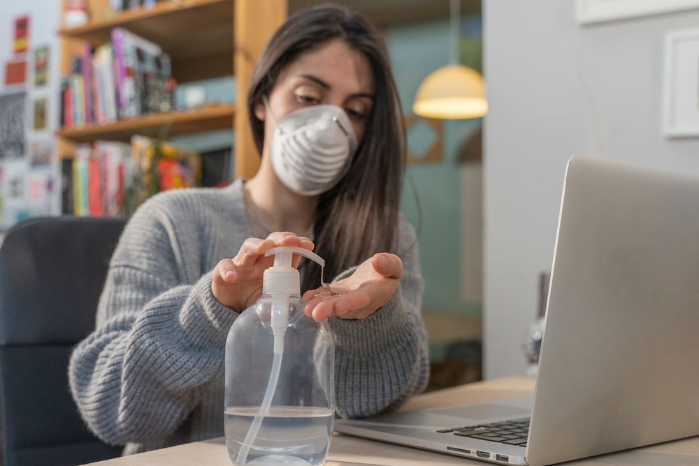 Business woman working from home wearing protective mask Cleaning her hands with sanitizer