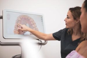 A woman dentist showing the patient on the screen the teeth