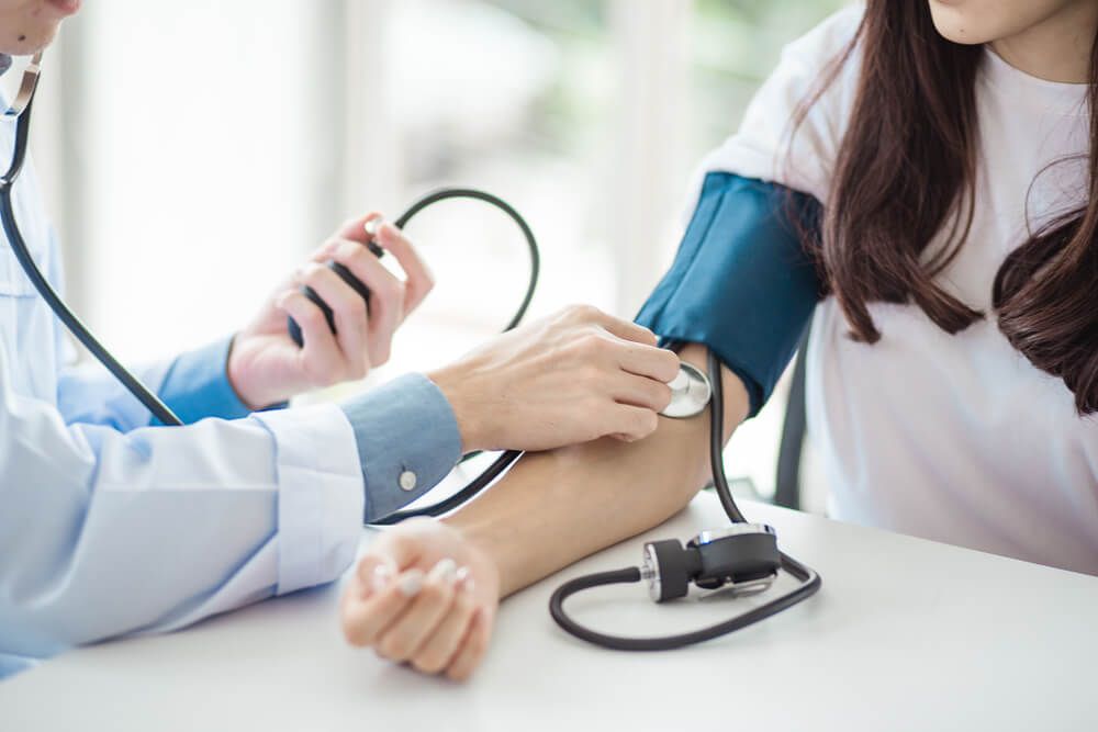 Doctor using sphygmomanometer with stethoscope checking blood pressure to a patient