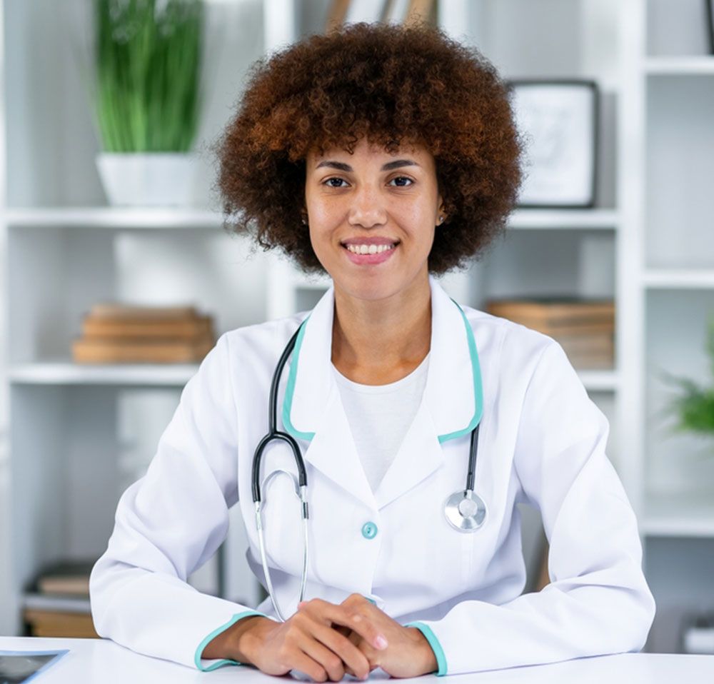 Confident female doctor sitting at office desk and smiling