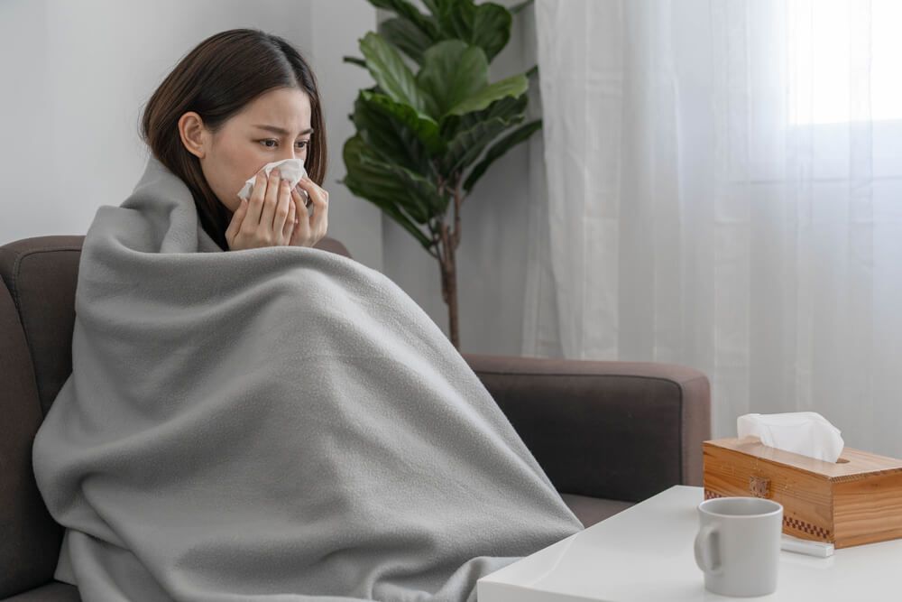 Sick woman with runny nose and cough at home