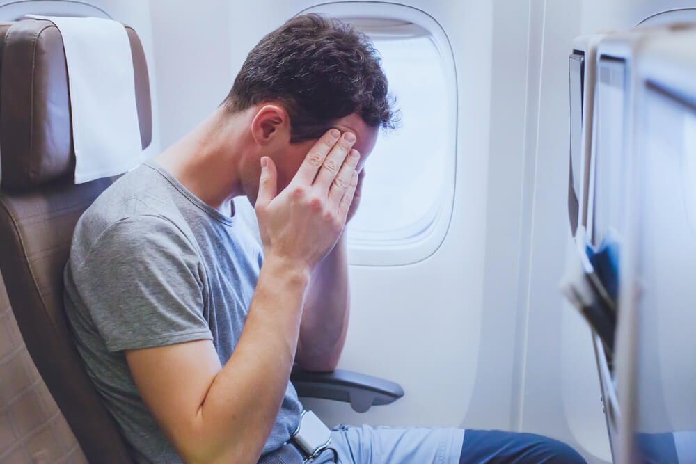 man passenger suffering from headache in the airplane