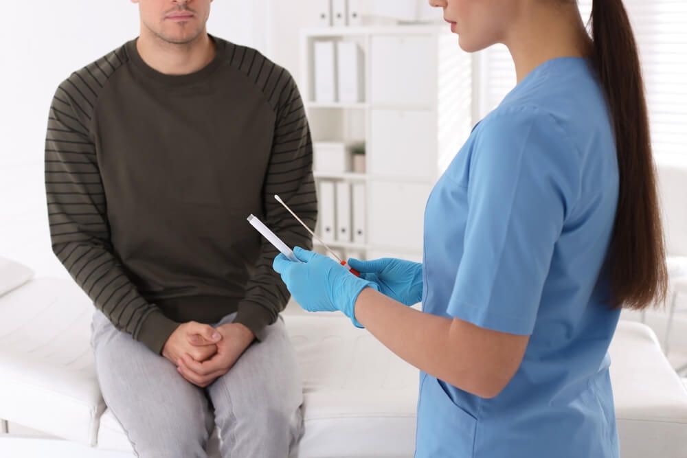 Doctor taking sample for STD testing from man in clinic
