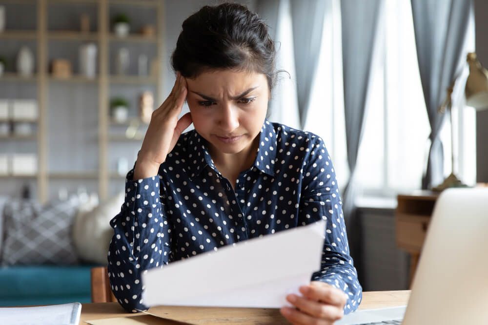 Disappointed woman sit at desk reding document