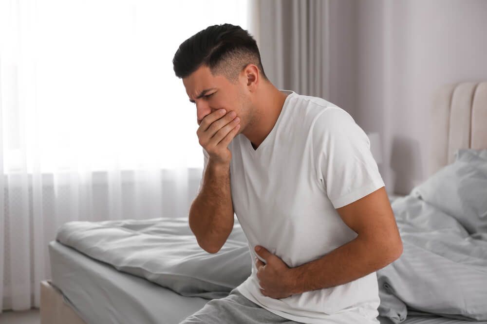 Man suffering from nausea on bed at home