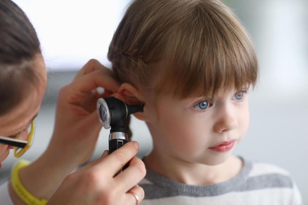 Otorhinolaryngologist examines little girl's ear with otoscope