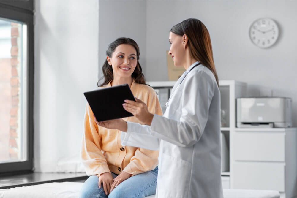 female doctor with tablet pc computer talking to smiling woman patient