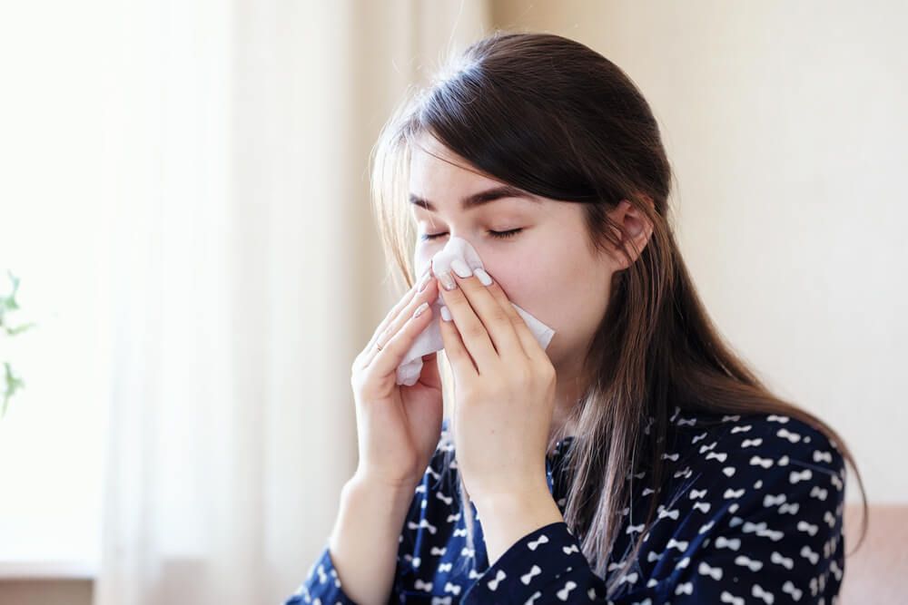 A sick exhausted woman blows a runny nose into a napkin