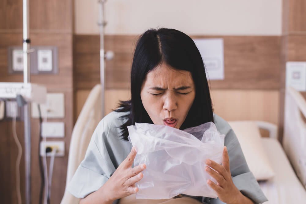 Woman patient vomiting into plastic bag