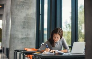 Shot,Of,Young,Asian,Female,Student,Sitting,At,Table,And