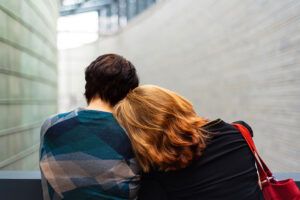 Brown haired woman with her head on his partner's shoulder