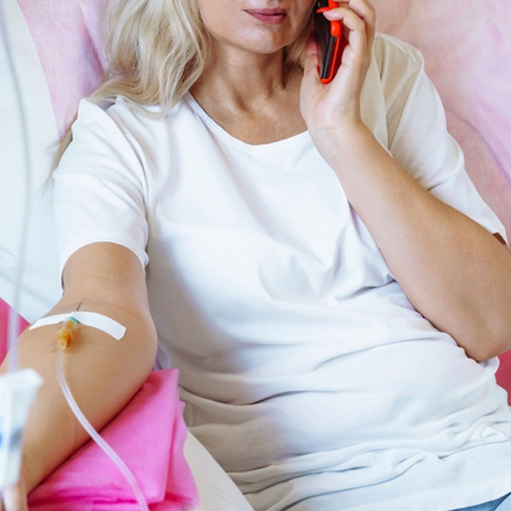 Woman in the hospital with a dropper in her hand talking on a mobile phone
