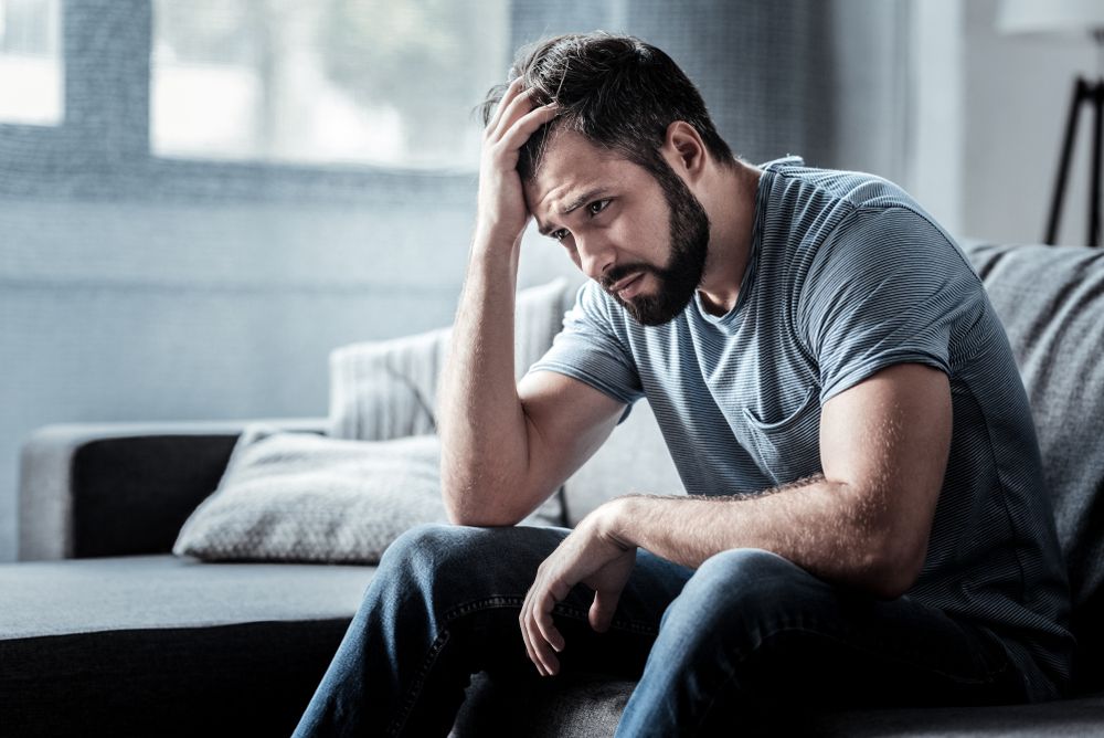 Sad unhappy handsome man sitting on the sofa