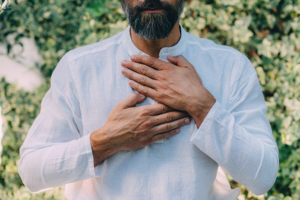 Man holding hands above the heart chakra.