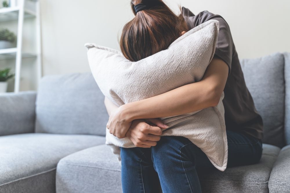 Unhappy anxiety young Asian woman covering her face with pillow