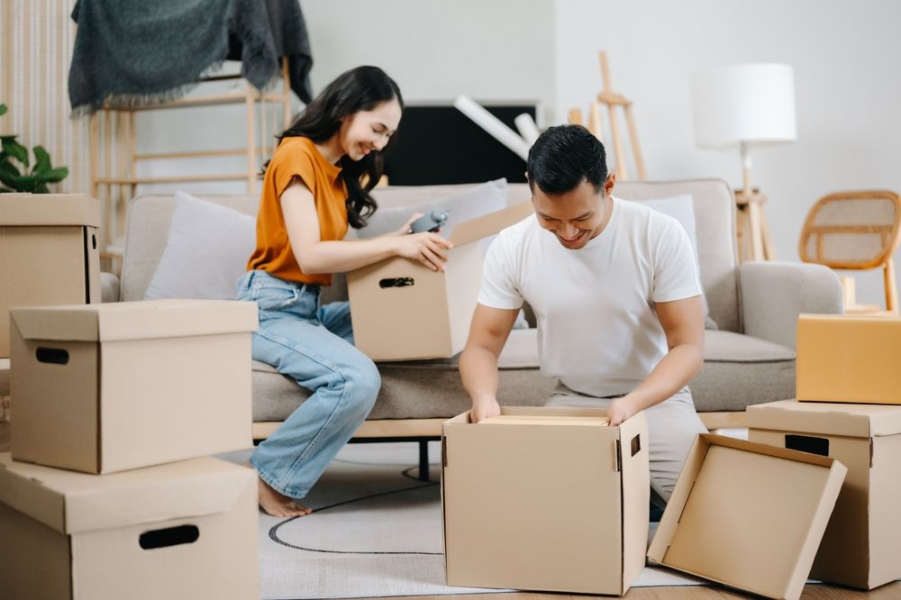 Happy young attractive couple man and woman with big boxes