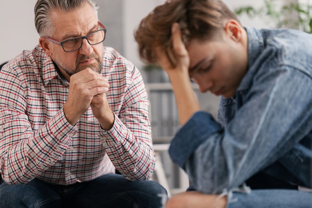 Professional counselor and troubled teenager during therapy meeting