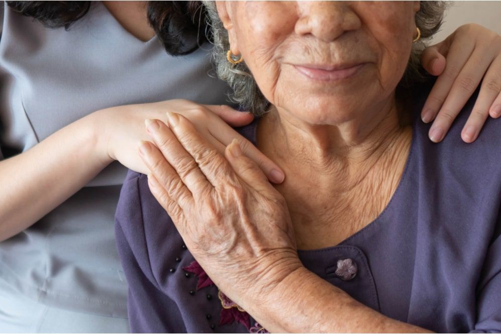 Friendly relationship between caregiver and happy eldery woman during nursing at home