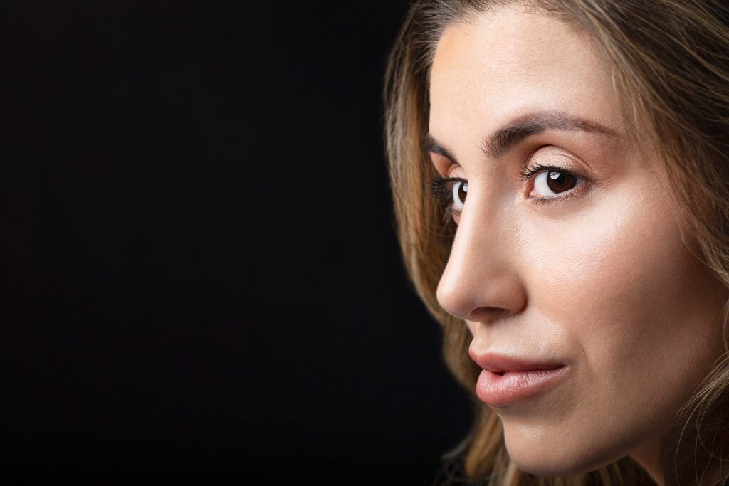 Beautiful woman looking to the side showcasing her stunning results of rhinoplasty surgery in Palo Alto, CA