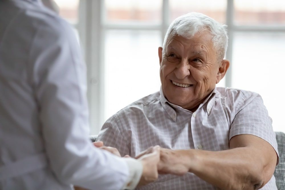 Doctor support retired older male patient holding his palms