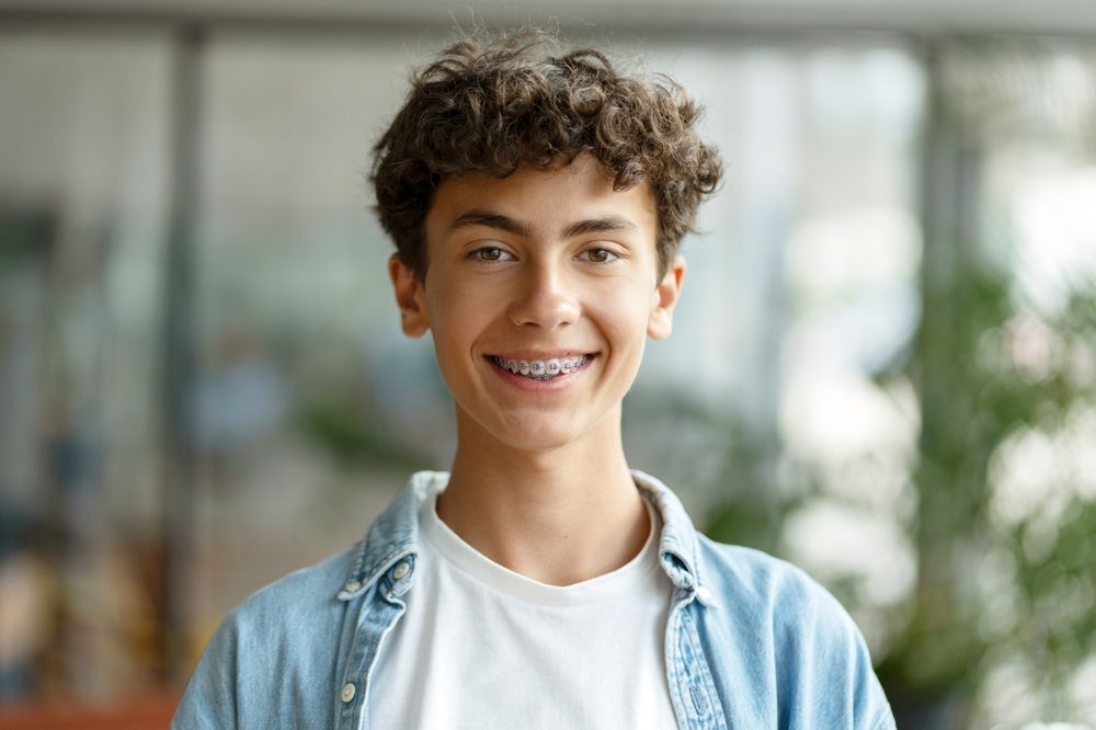 Smiling smart curly haired school boy wearing braces on teeth