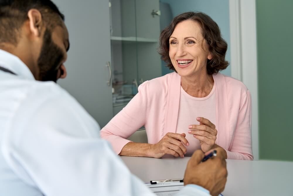 Happy mature female patient talking to male doctor