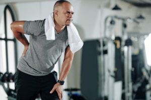 Mixed-race man suffering from low back pain after training in gym