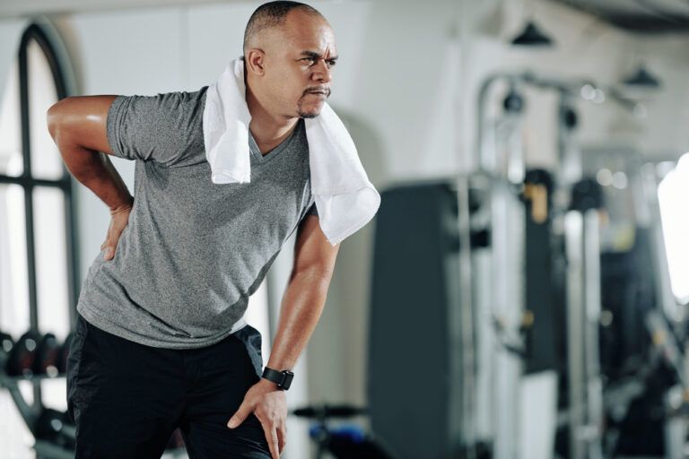 Mixed-race man suffering from low back pain after training in gym