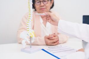 Elderly Patient consulting Doctor with Spine anatomy for Spinal Cord Disorder and disease