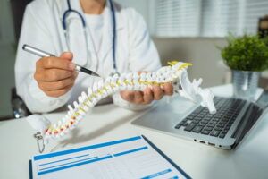 Specialist is analyzing a model of a spine showing the steps of a patient suffering spinal replacement surgery.