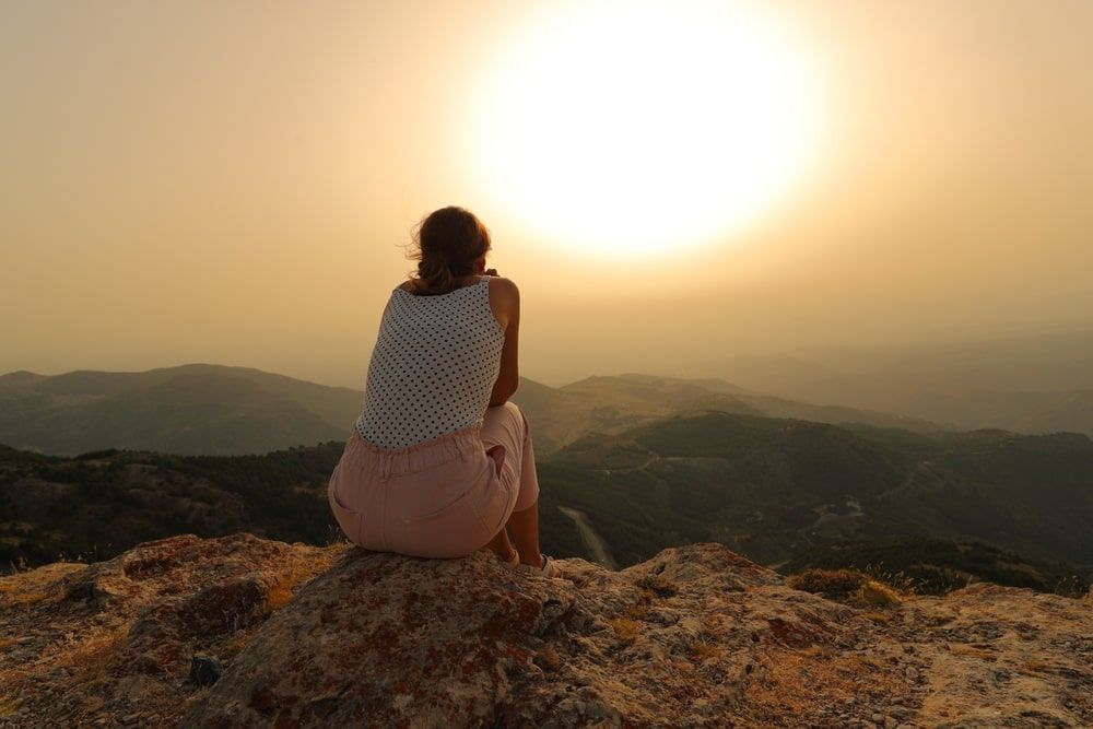 A woman alone contemplating sunset in the mountain