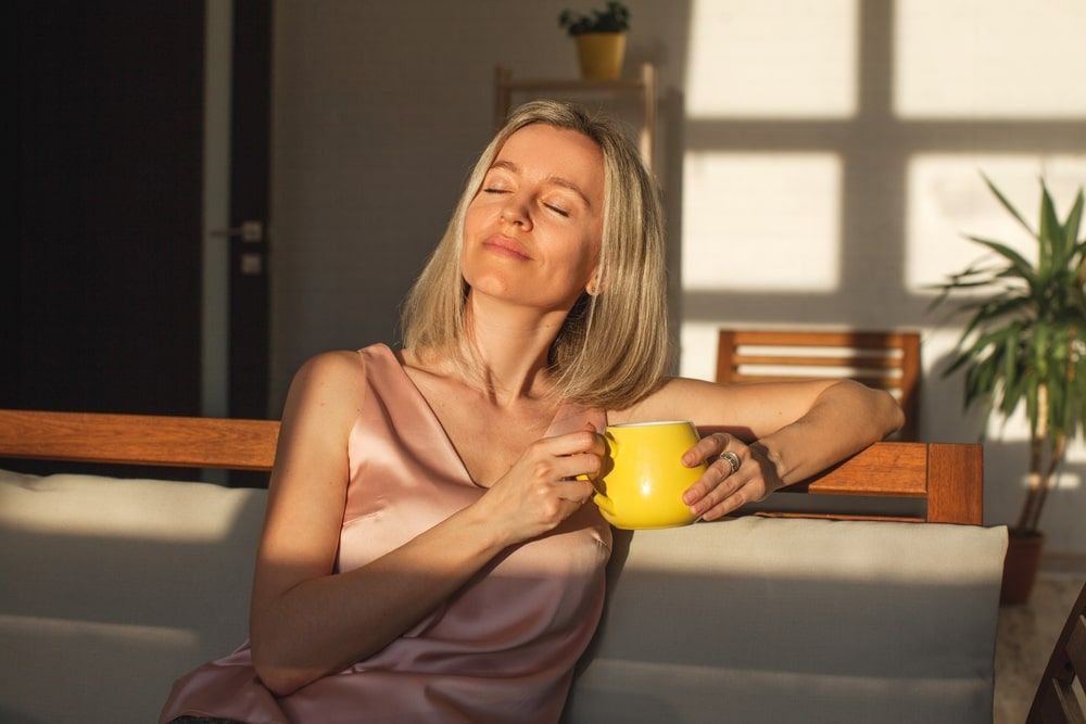 Satisfied middle aged woman is sitting on couch at home