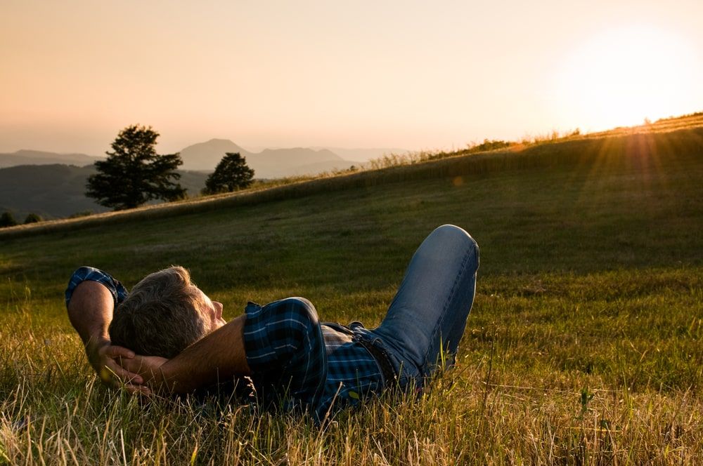 Man taking a break in a meadow in the wonderful warm light of the sunset