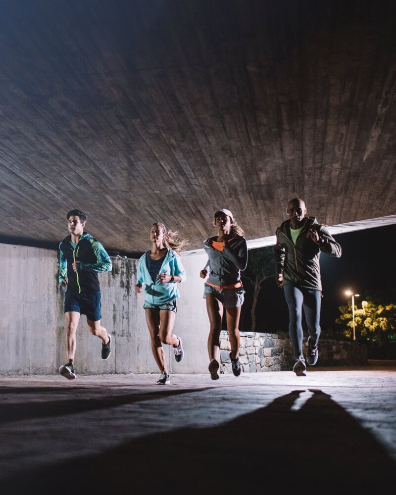 Group of young men and women running together at night