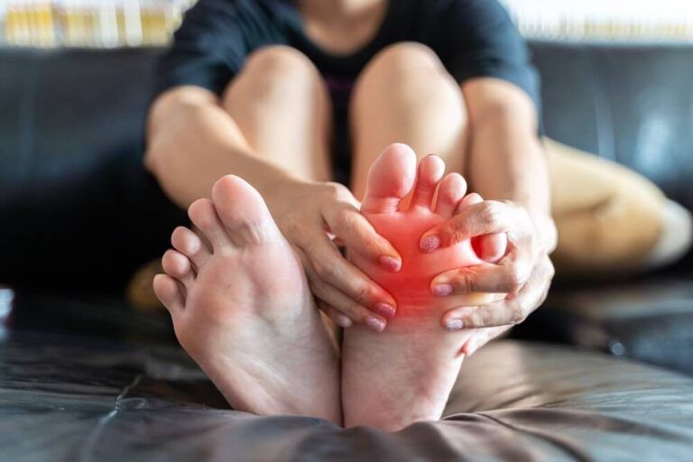 woman feeling pain in her foot at home