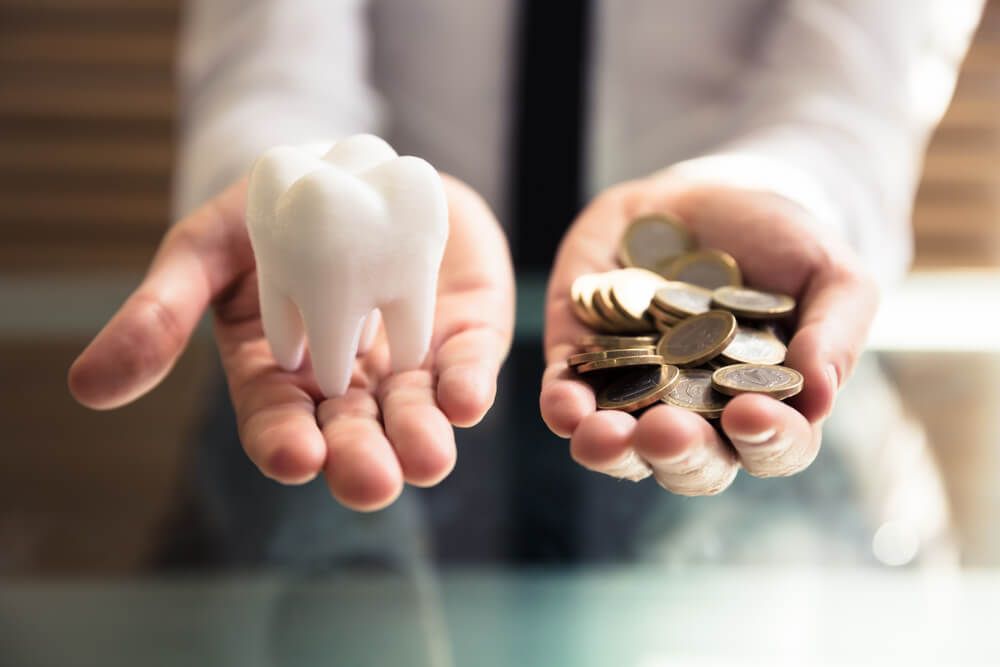 A Person's Hand Holding White Tooth And Golden Coins