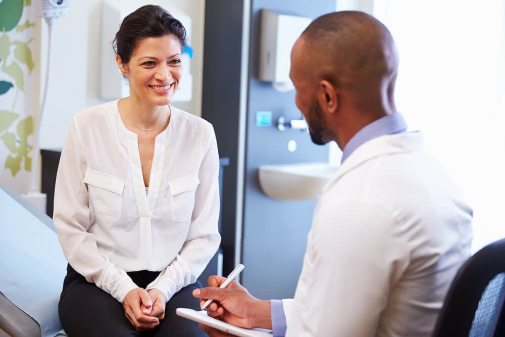 Female Patient And Doctor Have Consultation In Hospital Room