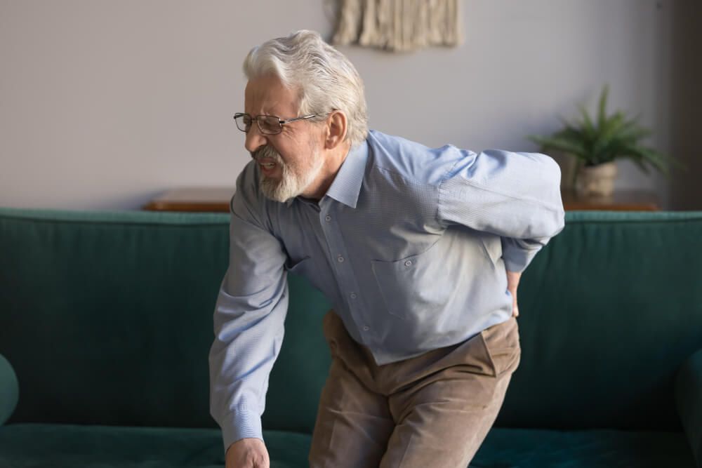 Aged man in glasses writhes in pain suffers from low back strain