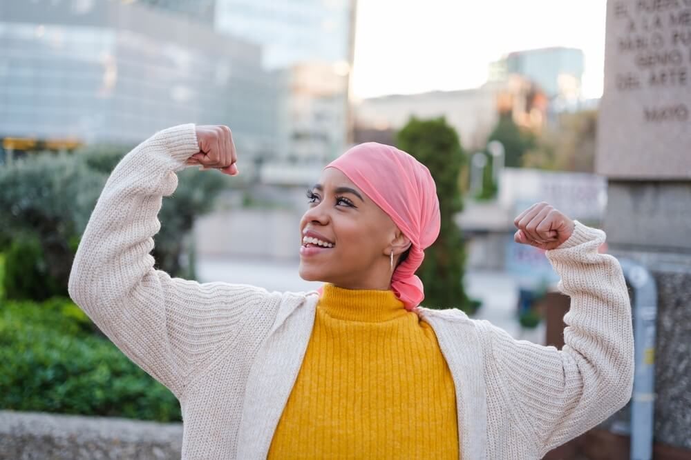Young woman in pink scarf fights cancer disease and feels strong to overcome it