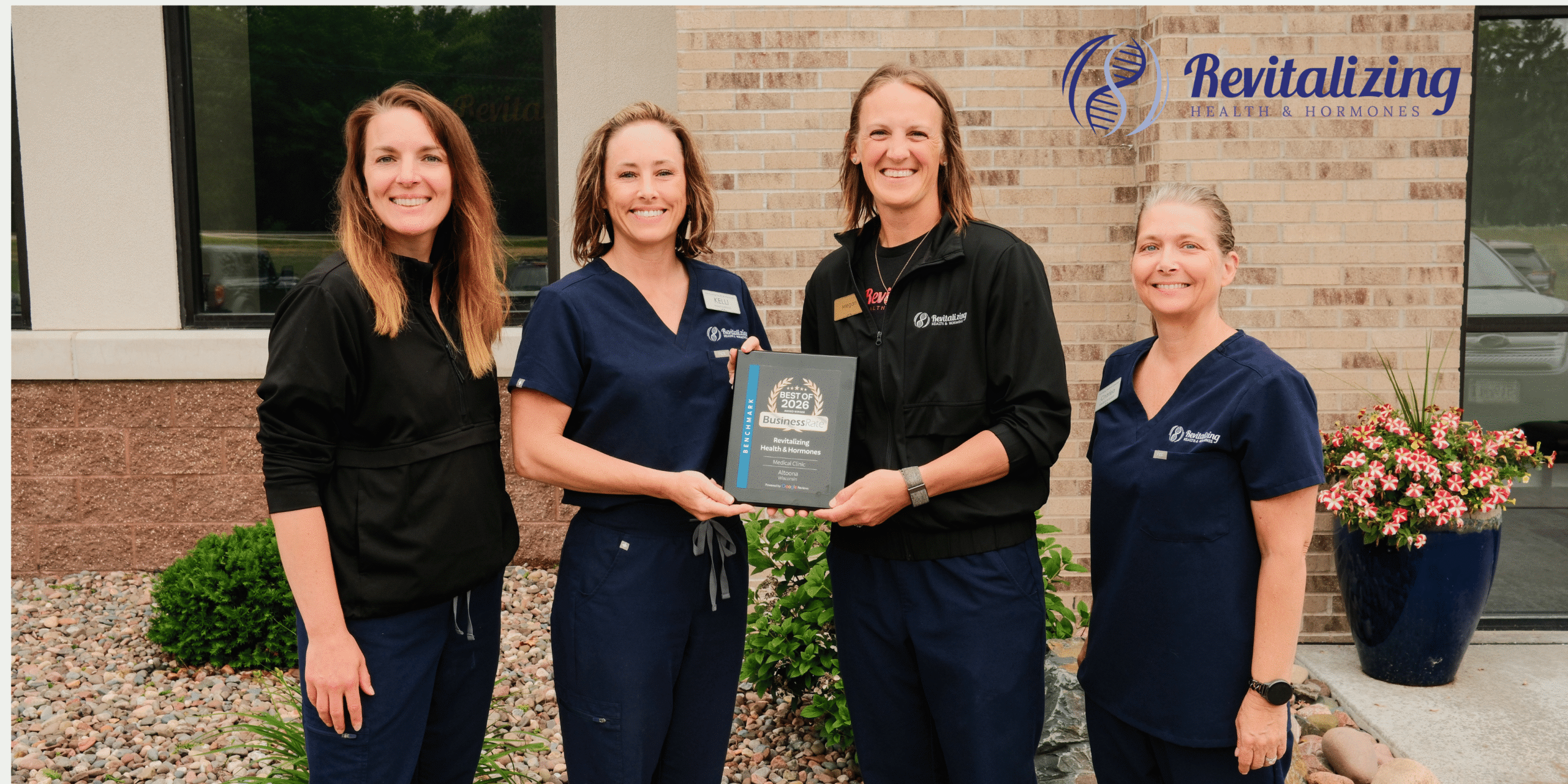 The Revitalizing Health & Hormones team poses together holding their BusinessRate award recognizing the clinic as the #1 Healthcare Clinic in Eau Claire County for excellence in patient care, reputation, and patient satisfaction.