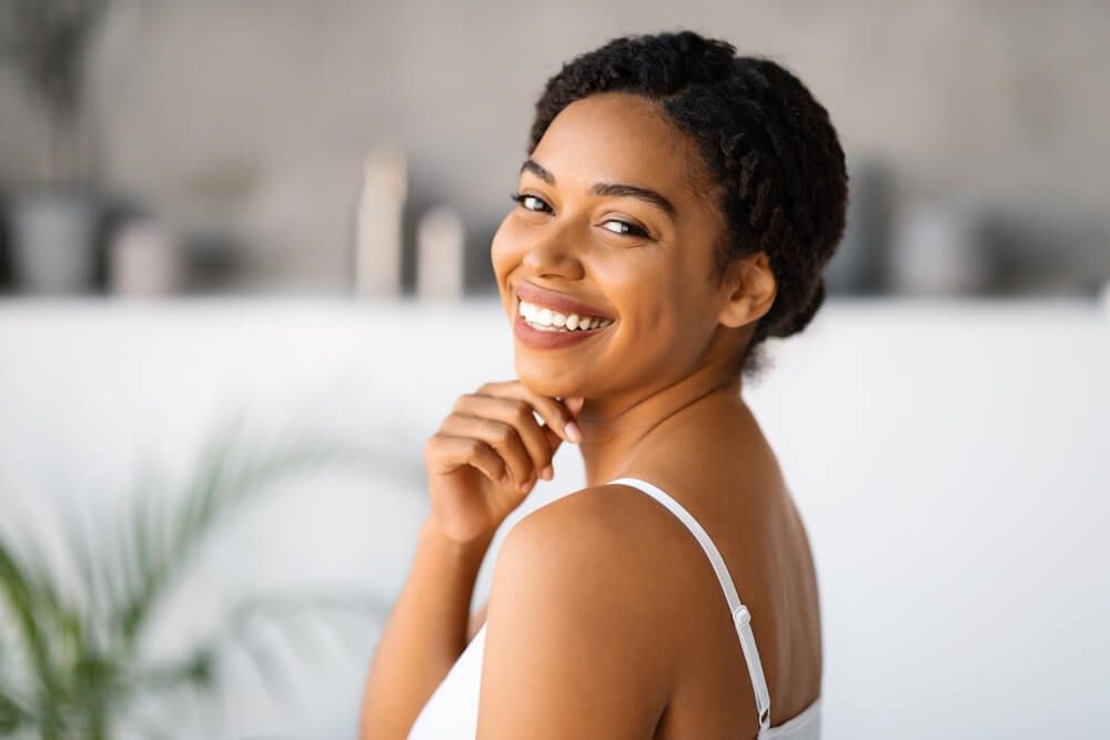 Natural Beauty. Attractive Black Woman Touching Chin And Looking At Camera While Standing In Bathroom At Home